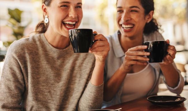 a couple of women holding coffee cups